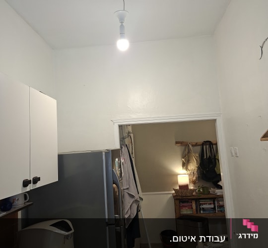מטבח עם מקרר, דלי צבע וספרים על מדף